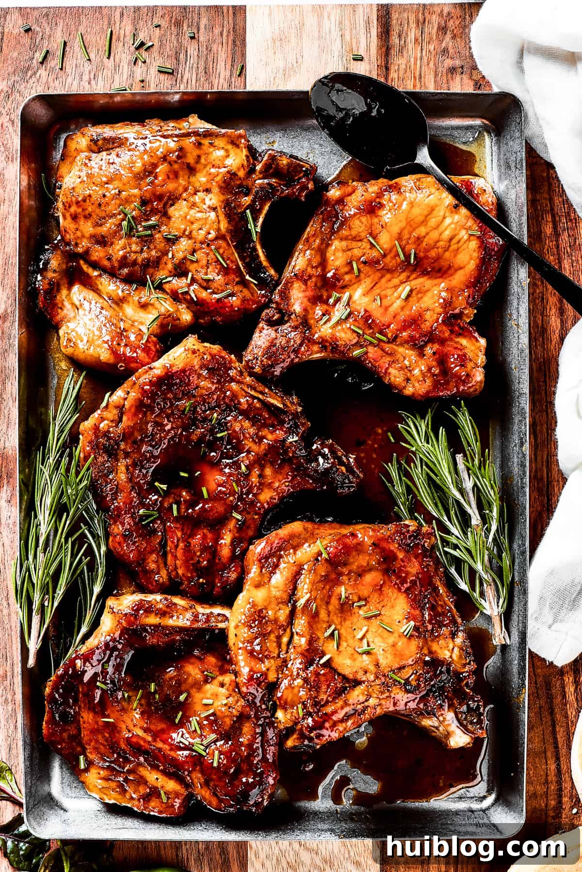 Gorgeous Brown Sugar Pork Chops may look fancy, but they are actually so simple to make! Savory, pan-fried chops with brown sugar glaze. A tray of beautifully cooked brown sugar pork chops with fresh herbs scattered on top.
