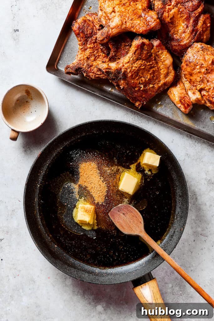 Gorgeous Brown Sugar Pork Chops may look fancy, but they are actually so simple to make! Savory, pan-fried chops with brown sugar glaze. Melted butter, brown sugar, and liquid being stirred together in a skillet to form a pan sauce.