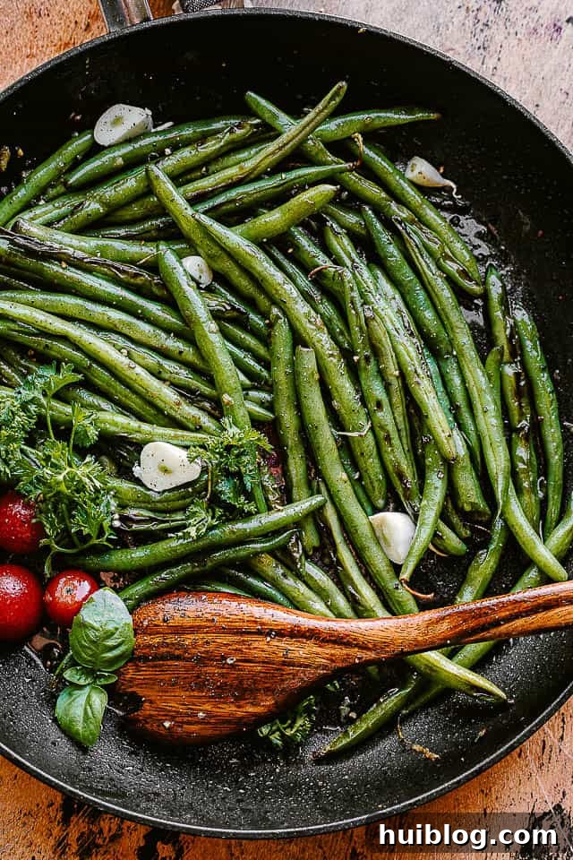 green beans cooking in a black skillet, perfectly charred and glistening with butter