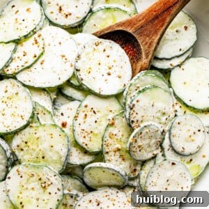 A vibrant bowl of creamy cucumber salad, generously coated in sour cream dressing and sprinkled with fresh black pepper