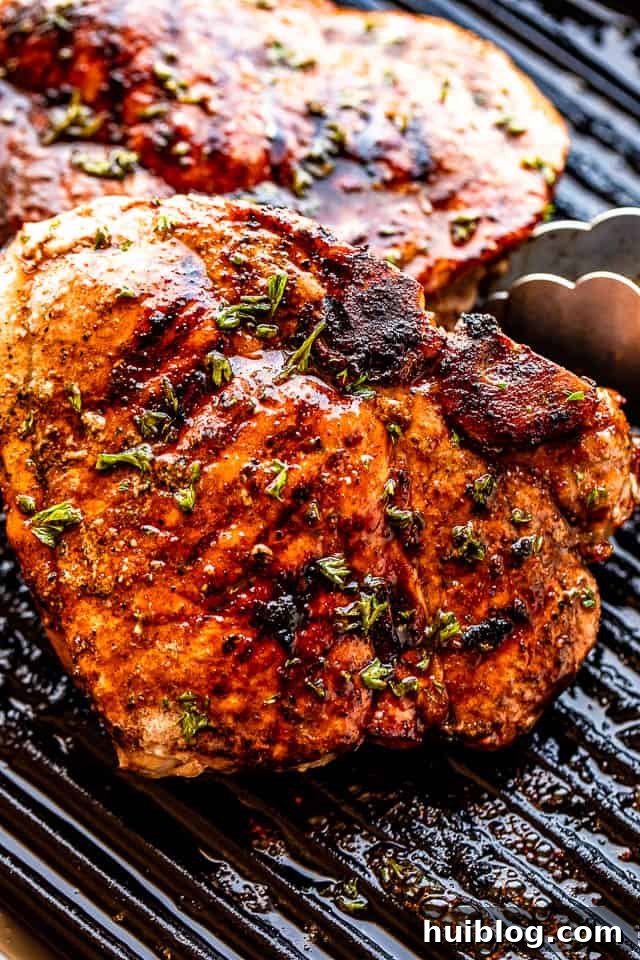 Tongs turning over grilled pork chops on a hot grill, showing perfect char marks and juicy interior.