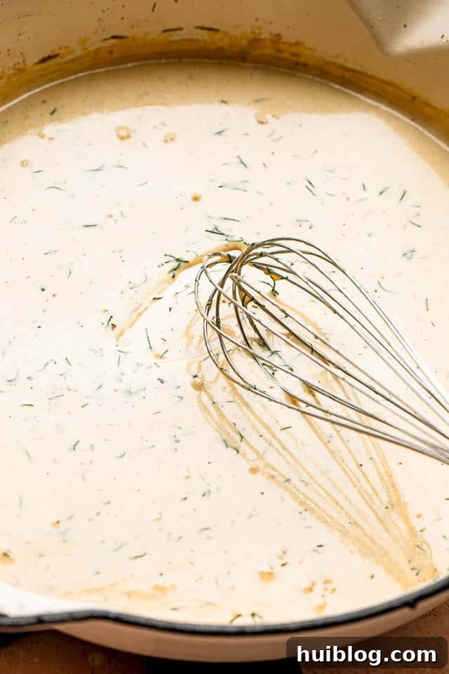 whisking a cream sauce inside a white pan