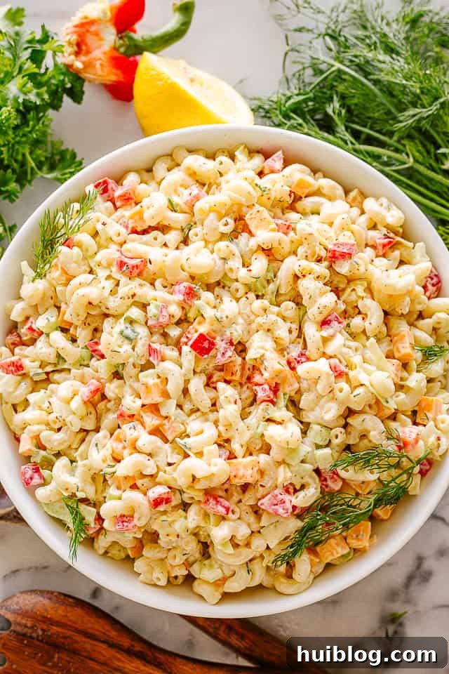 Creamy Macaroni Salad Recipe - So Much Flavor! Bowl of creamy macaroni salad, garnished with fresh herbs