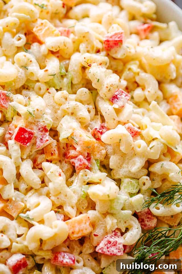 This macaroni salad is zesty, creamy, and full of great flavor and texture. Perfect for family gatherings or as a side to any weeknight meal! Close up of macaroni salad with vibrant vegetables.