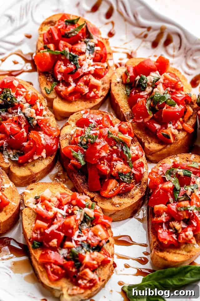 white platter with toasted bread sliced covered in tomato salad with balsamic glaze
