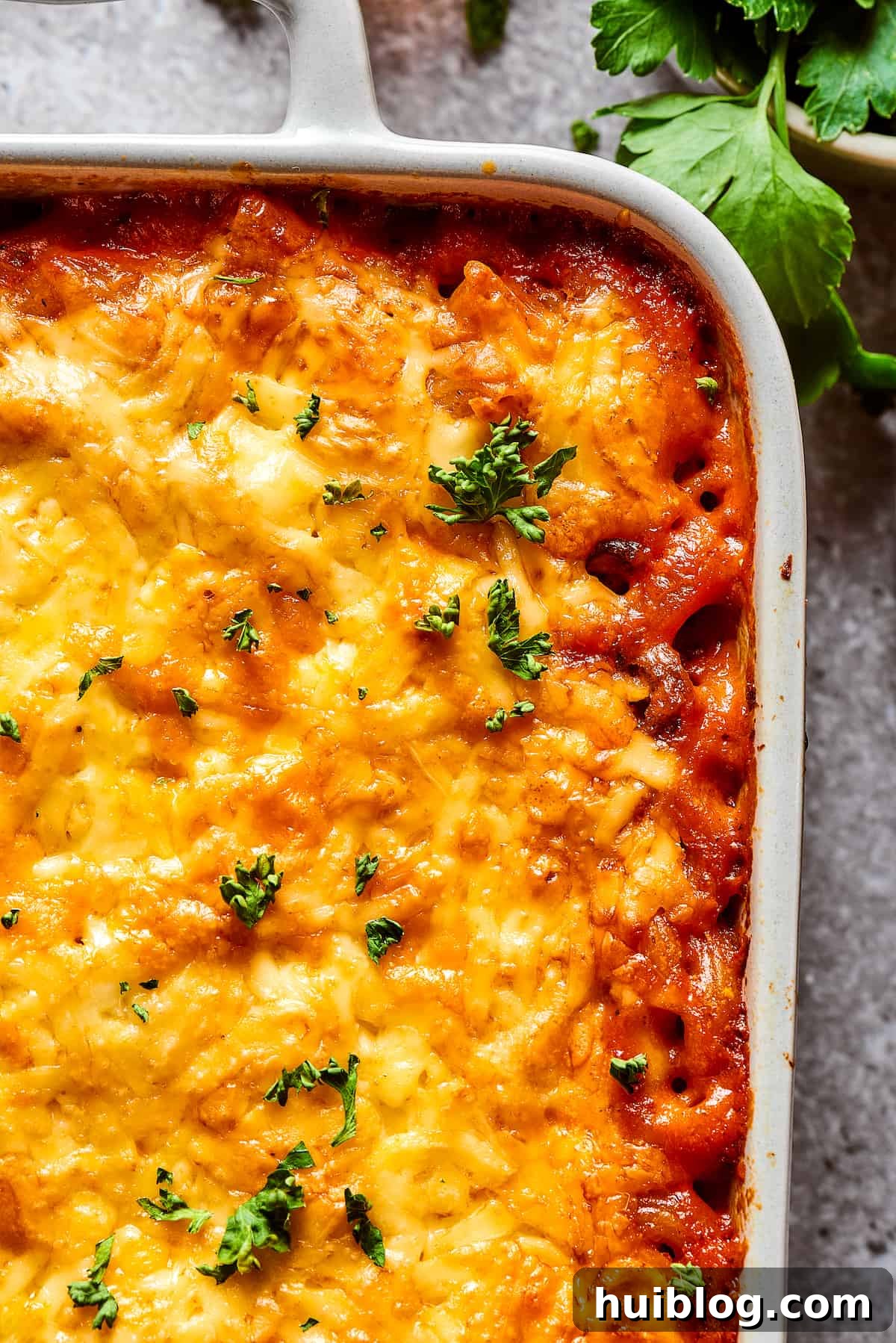 Close-up shot of the corner of a cheeseburger casserole, showing the crispy, bubbly cheese and tender pasta.