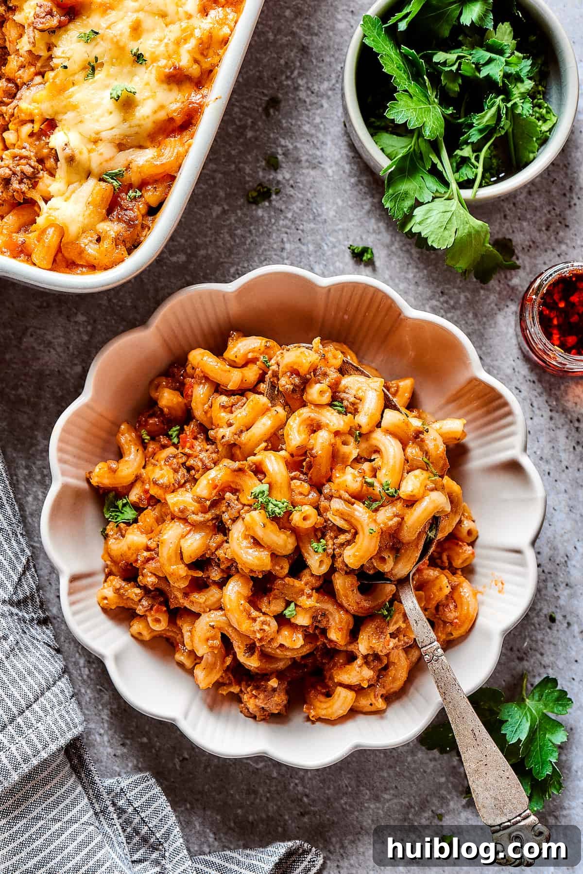 A serving of cheeseburger casserole in a bowl with fluted edges, garnished and ready to eat.