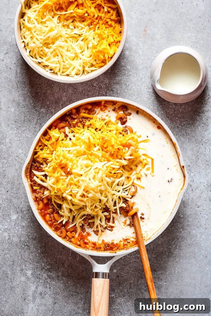 Stirring in luscious heavy cream and generous amounts of shredded cheese into the warm skillet dish.