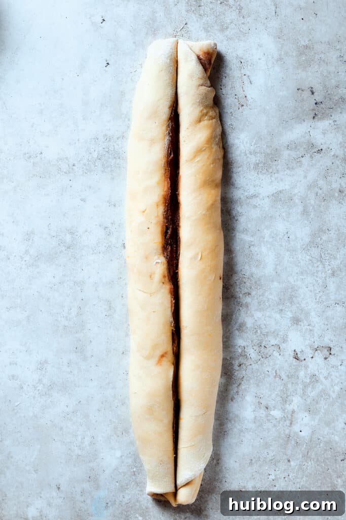 Slicing a roll of dough lengthwise.
