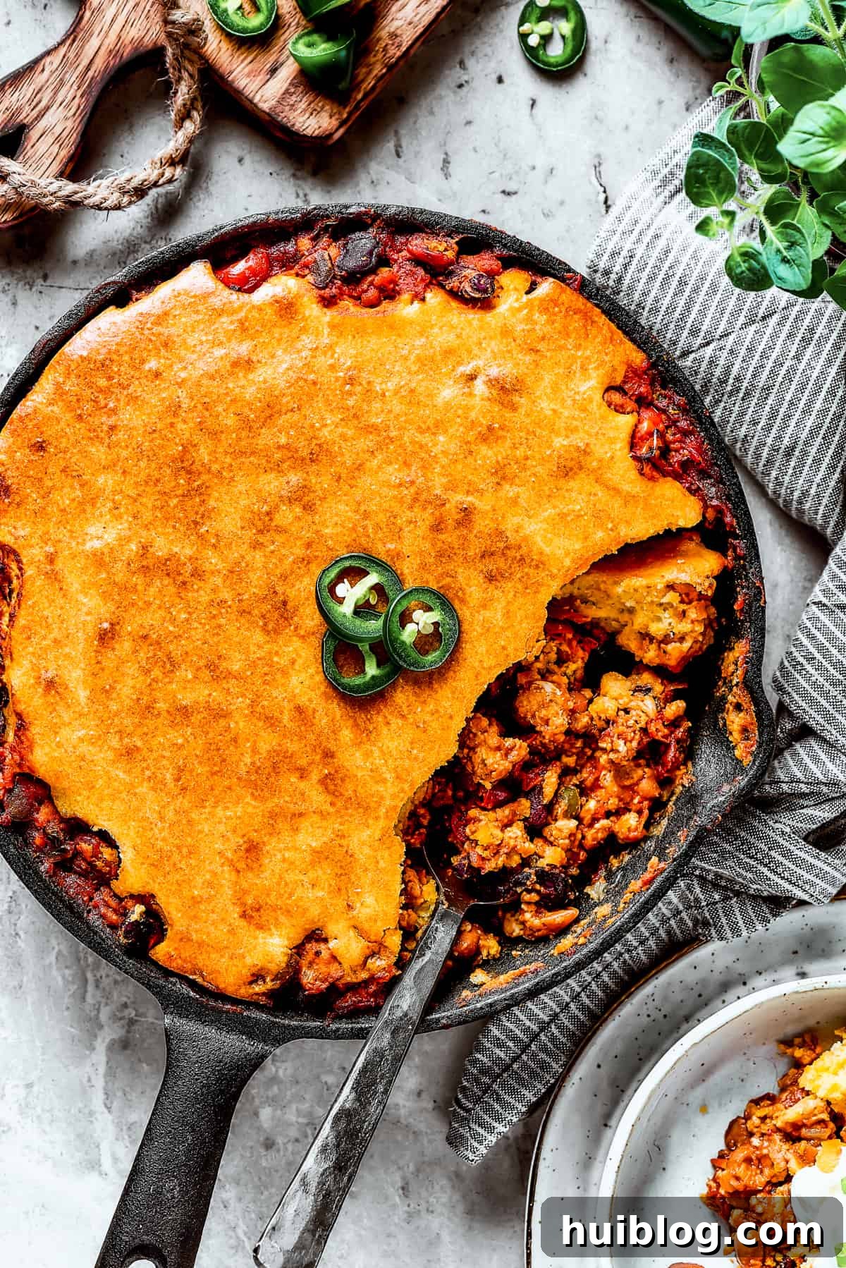 Overhead shot of a cast iron skillet with homemade Chili cornbread casserole and a serving removed with a spoon.