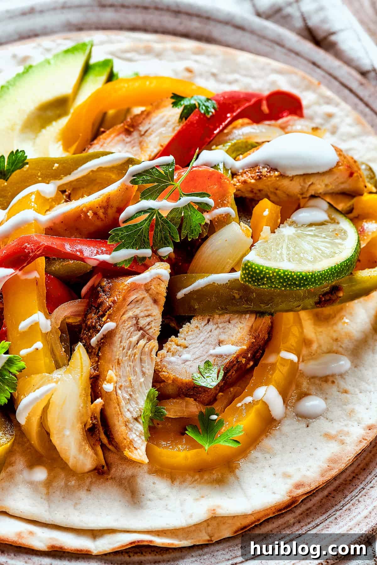 A serving of slow cooker chicken fajitas generously topped with creamy sour cream and a sprinkle of fresh cilantro.