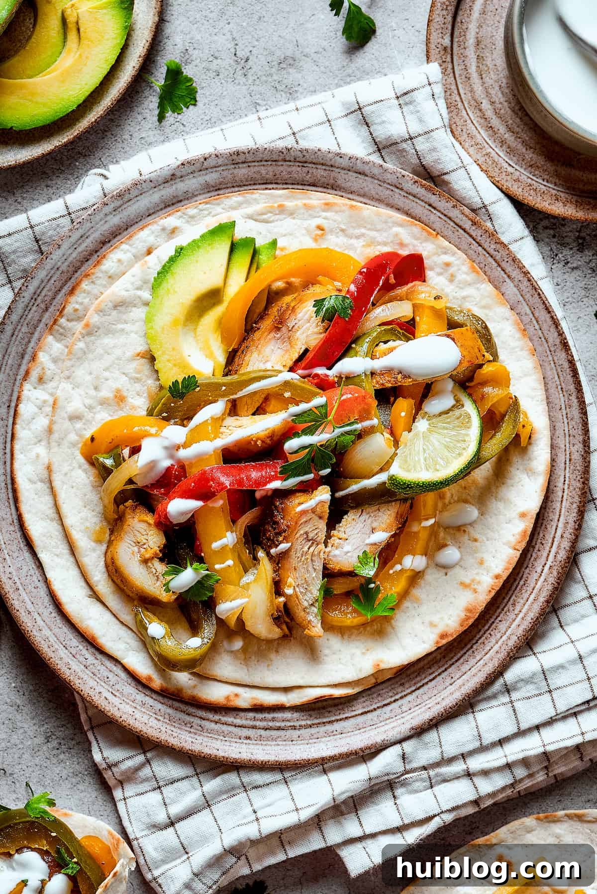 Beautifully plated crockpot chicken fajitas, adorned with fresh lime, creamy avocado slices, and a dollop of sour cream, ready to be enjoyed.