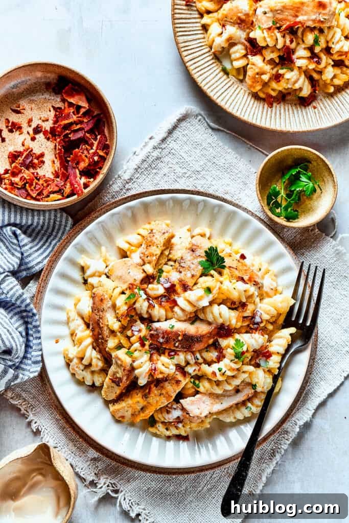 Overhead view of delicious Chicken Bacon Ranch Pasta ready to be enjoyed. An overhead shot of two dinner plates, each featuring a generous serving of Chicken Bacon Ranch Pasta, beautifully garnished.