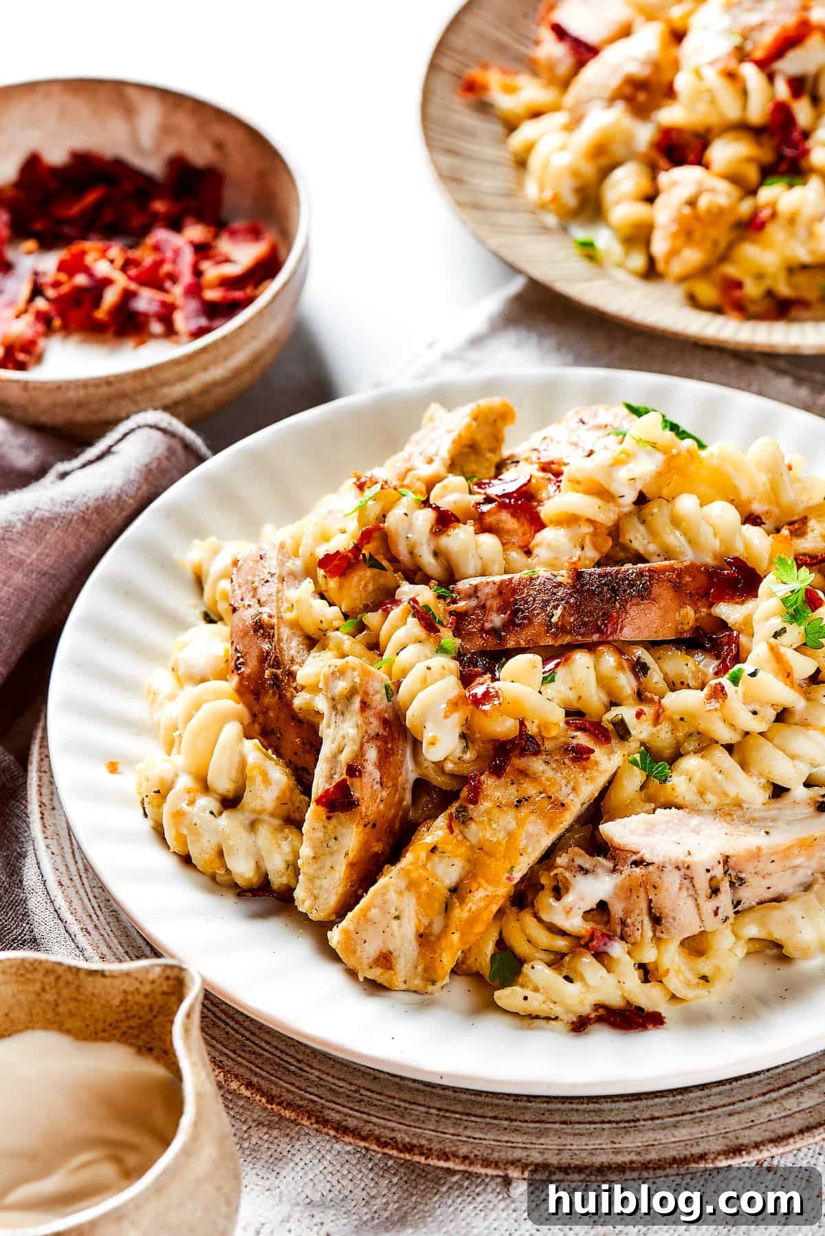 Hearty and Cozy Chicken Bacon Ranch Pasta for a delicious dinner! Two plates filled with creamy chicken bacon ranch pasta, garnished with fresh herbs, ready to be served.