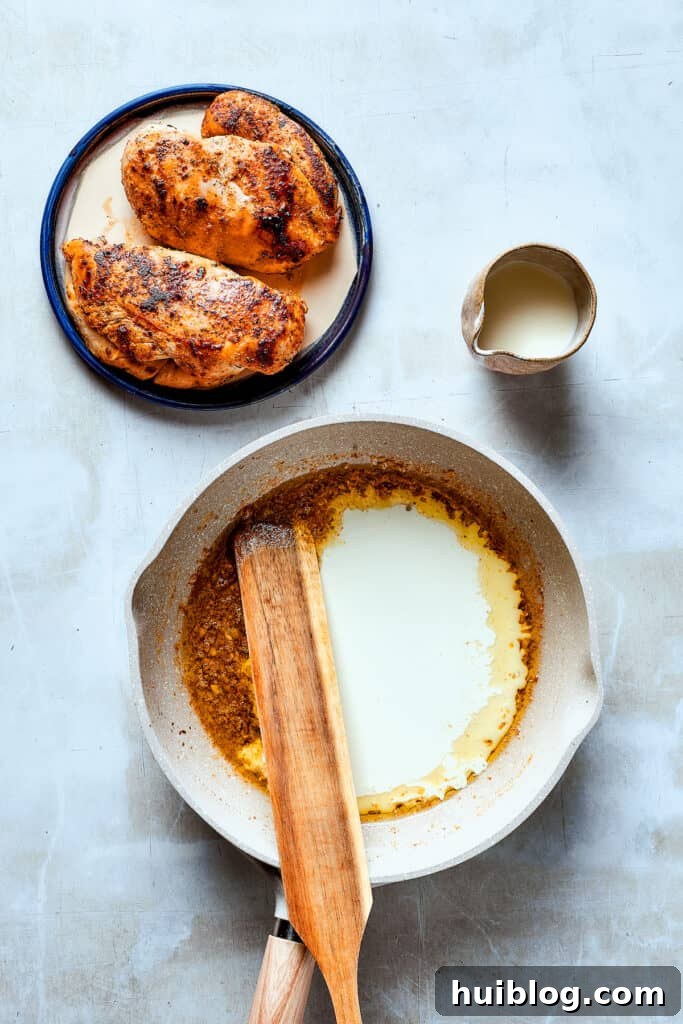 Stirring the rich and creamy ranch sauce in the skillet. A wooden spoon stirring a creamy, bubbling sauce in a skillet, ensuring all ingredients are well combined.