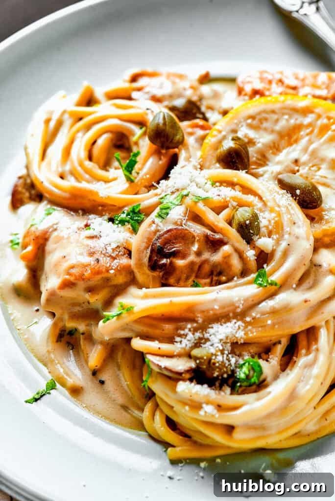 This chef’s-kiss-perfect Chicken Piccata Cheesecake Factory Copycat is loaded with juicy chicken, mushrooms, and pasta in a creamy sauce. Close-up shot of creamy pasta with capers, lemon, and chicken.