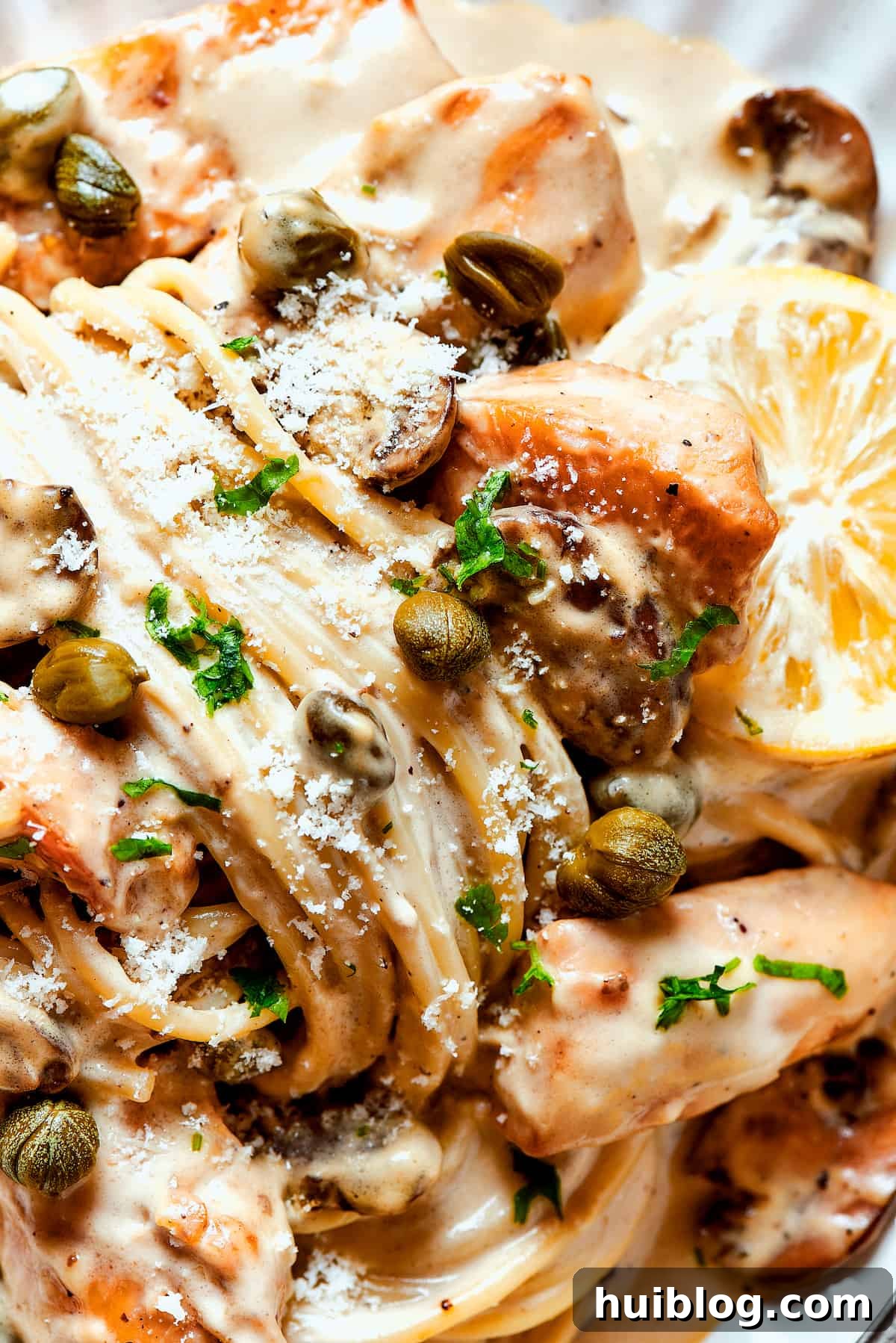 This chef’s-kiss-perfect Chicken Piccata Cheesecake Factory Copycat is loaded with juicy chicken, mushrooms, and pasta in a creamy sauce. Close-up shot of creamy pasta with capers, lemon, and chicken piccata.