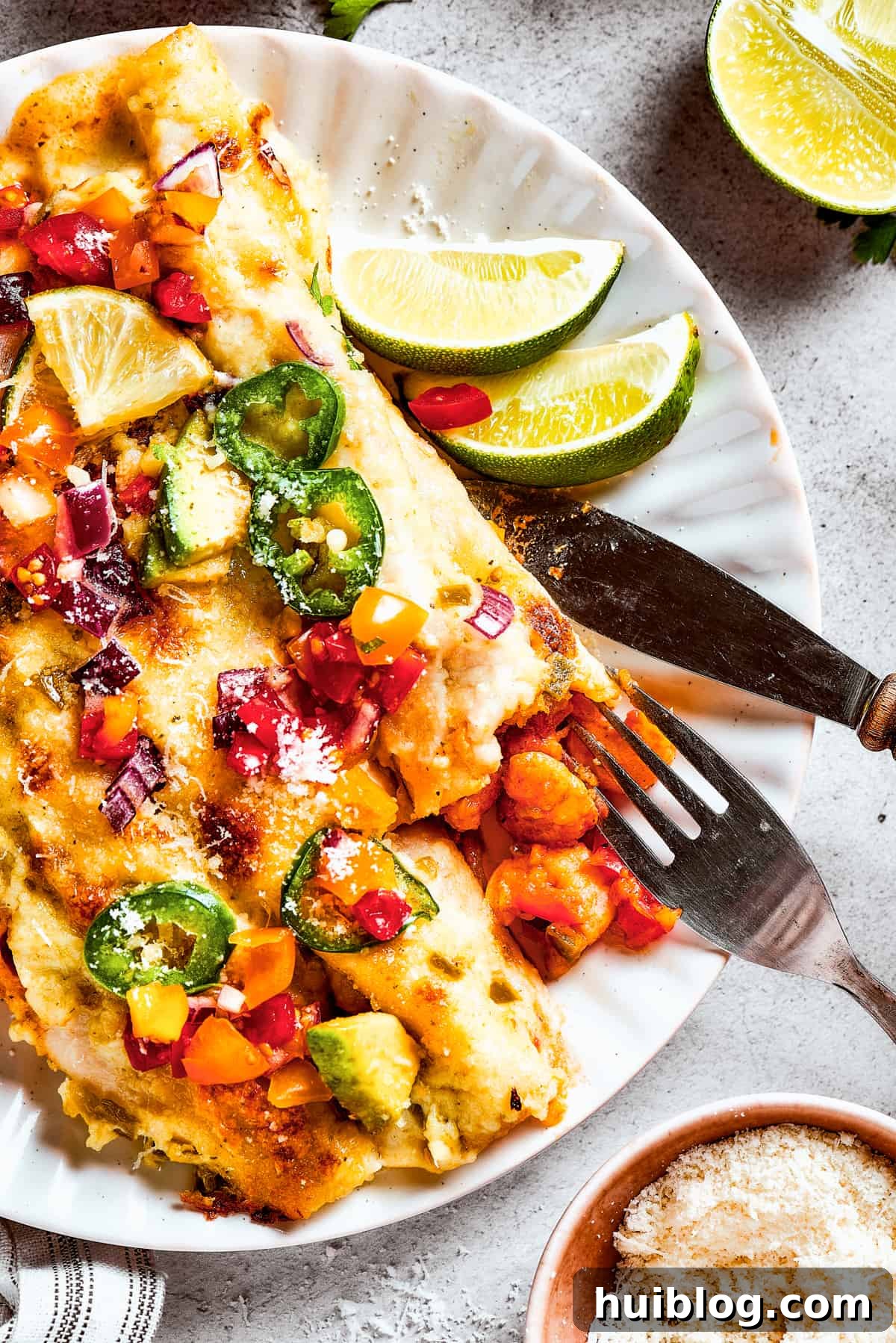 Shrimp Enchiladas are an easy, cheesy dinner with chopped shrimp and green enchilada sauce. The perfect balance of creamy, spicy, and savory! A plate of enchiladas topped with avocado and other toppings.