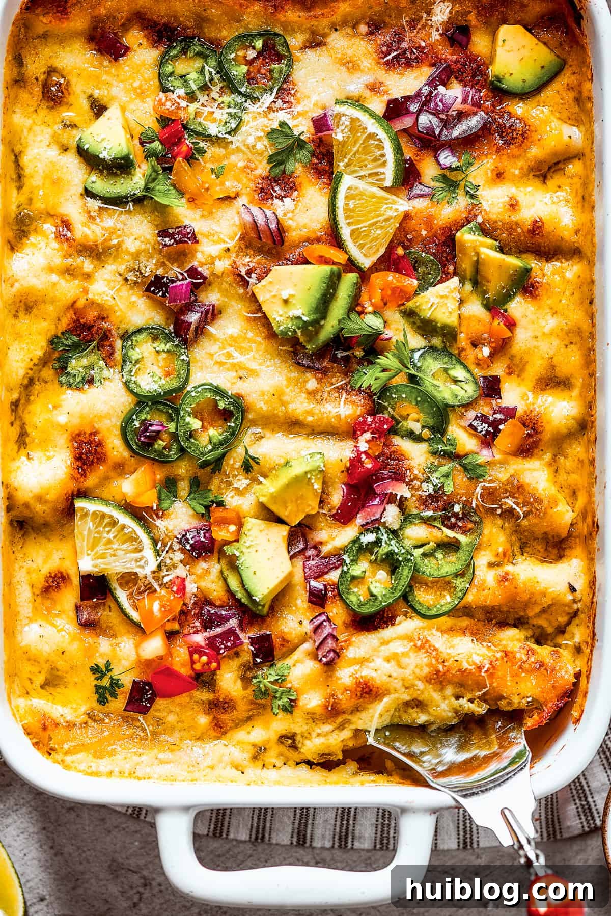 Shrimp Enchiladas are an easy, cheesy dinner with chopped shrimp and green enchilada sauce. The perfect balance of creamy, spicy, and savory! Photo of the bottom corner of a baking dish of homemade shrimp enchiladas.