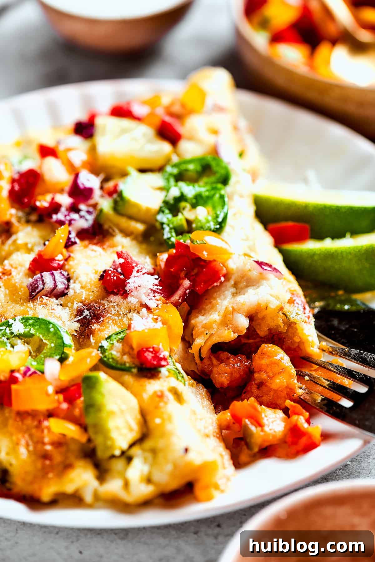 Shrimp Enchiladas are an easy, cheesy dinner with chopped shrimp and green enchilada sauce. The perfect balance of creamy, spicy, and savory! A plate of enchiladas topped with avocado and other toppings.