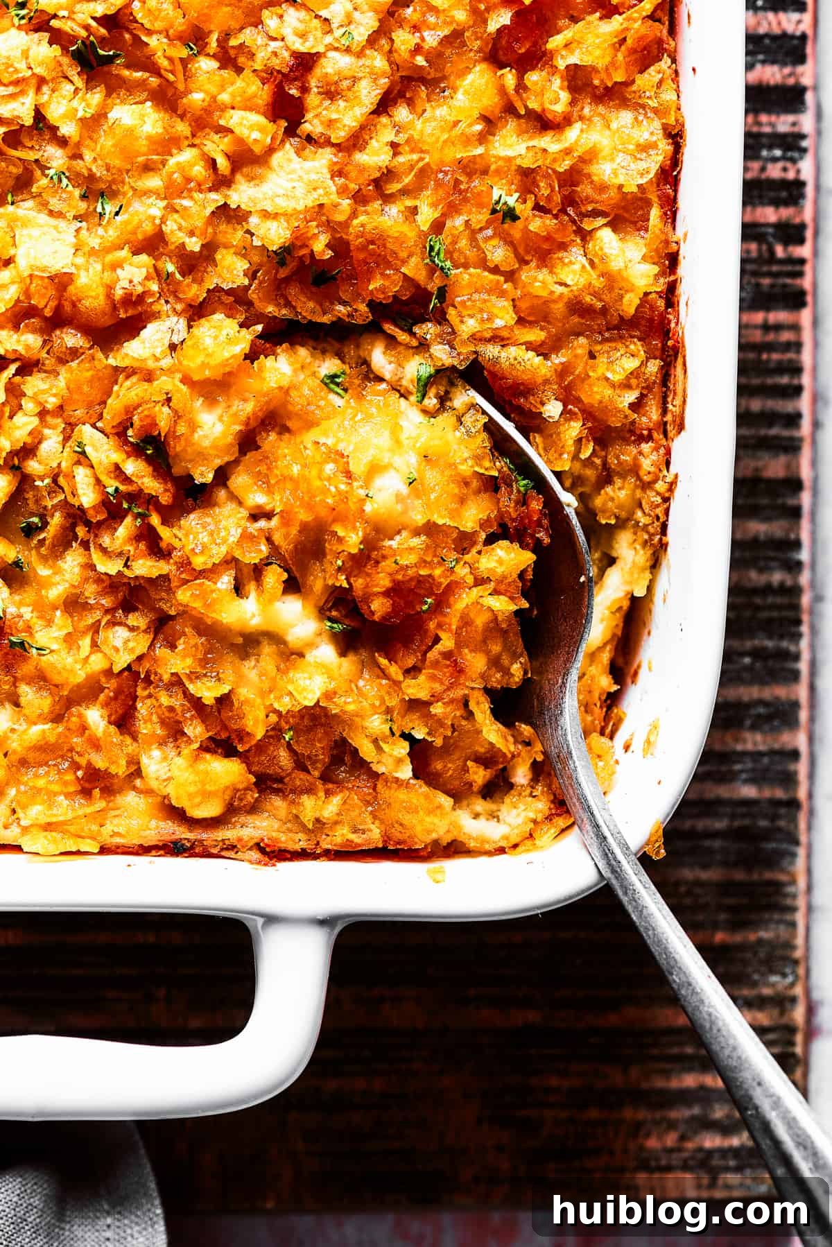 Close-up shot of a serving spoon in a casserole topped with cornflakes.