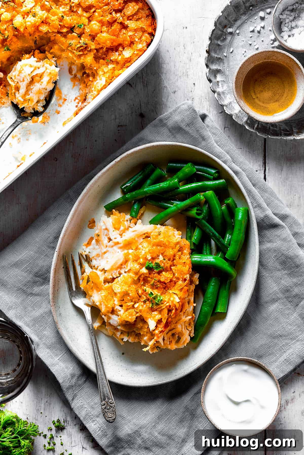 Overhead shot of hashbrown casserole on a dinner plate with green beans.