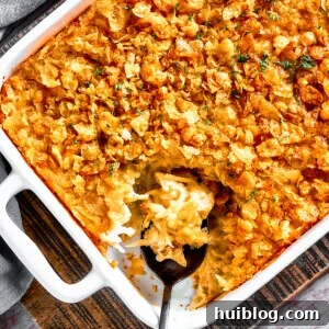 A casserole dish with hashbrown casserole. Some of it has been spooned out, and a serving spoon is set inside the casserole dish.