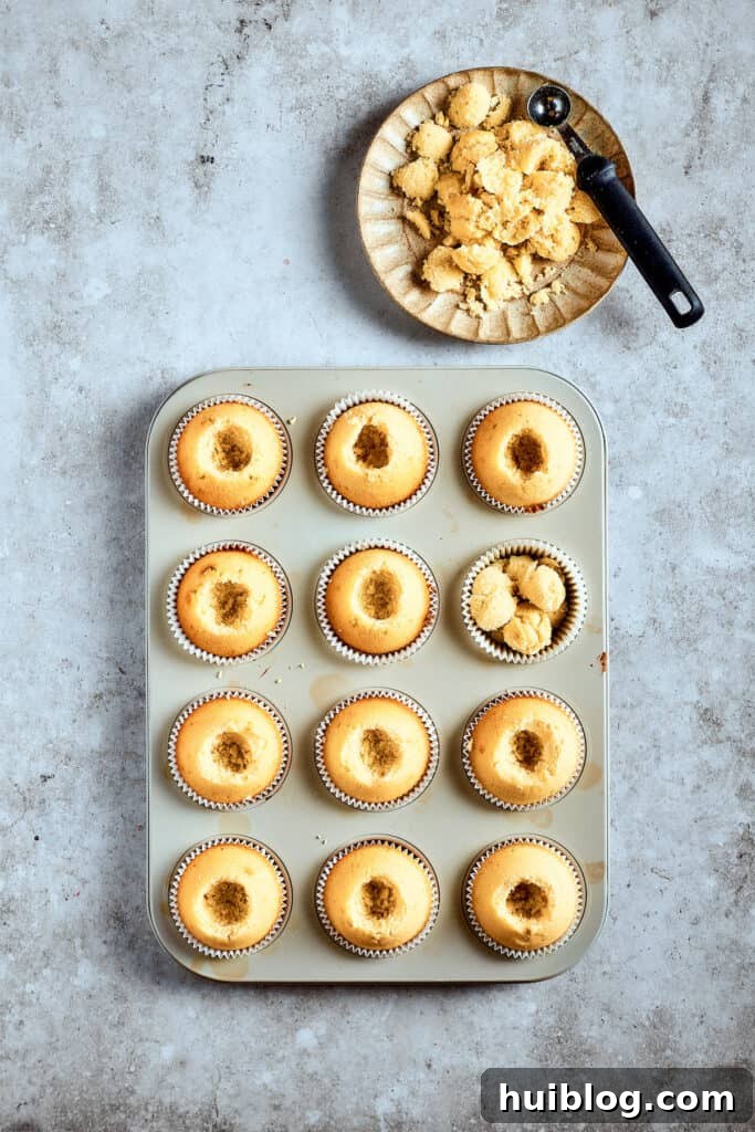 Cored cupcakes, awaiting their delicious filling. Baked cupcakes in a cupcake pan with their centers neatly cored out, ready to be filled with creamy banana pudding.
