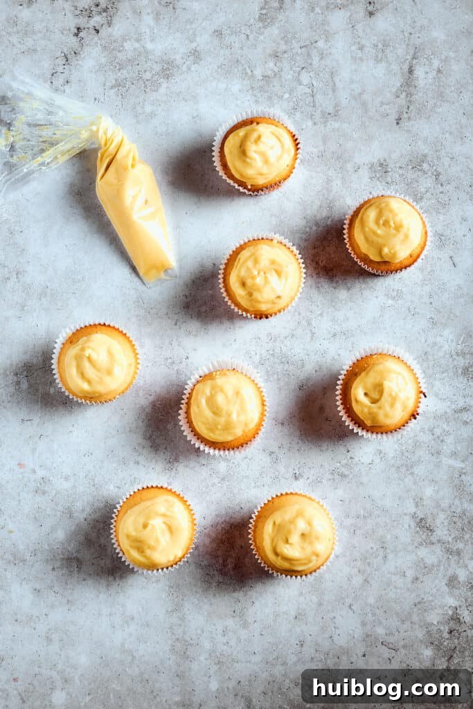 Cupcakes transformed with a rich pudding filling. Cupcakes generously filled and topped with a smooth layer of banana pudding, ready for the final whipped cream and garnishes.