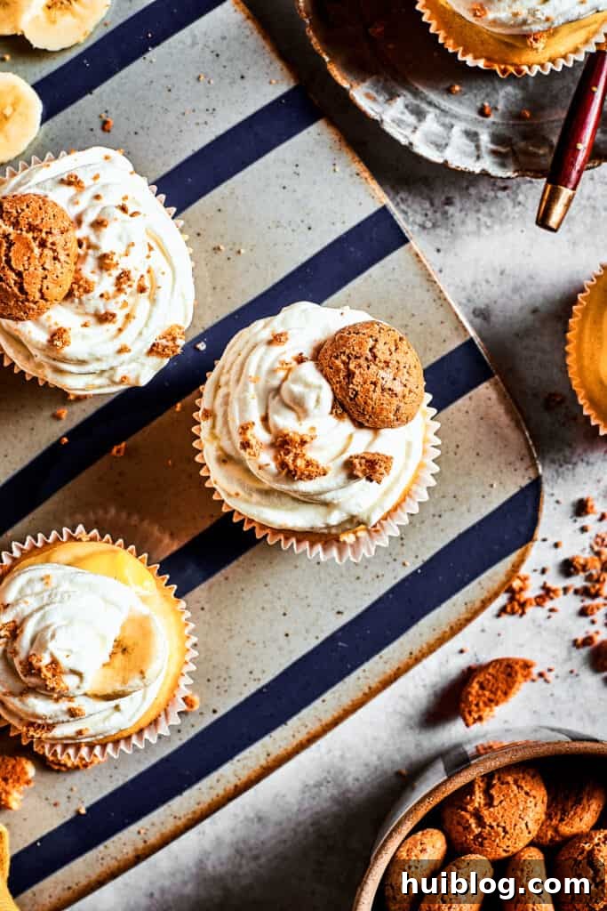 A stunning display of finished Banana Pudding Cupcakes. An overhead view of beautifully frosted banana pudding cupcakes arranged on a decorative silver platter, showcasing their enticing toppings.