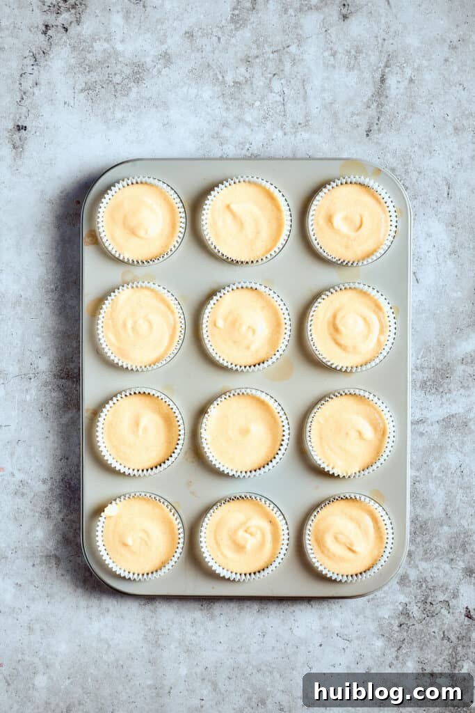 Perfectly portioned cupcakes, awaiting their bake. A cupcake pan filled with unbaked batter, neatly arranged in liners, ready for the oven to transform into fluffy treats.