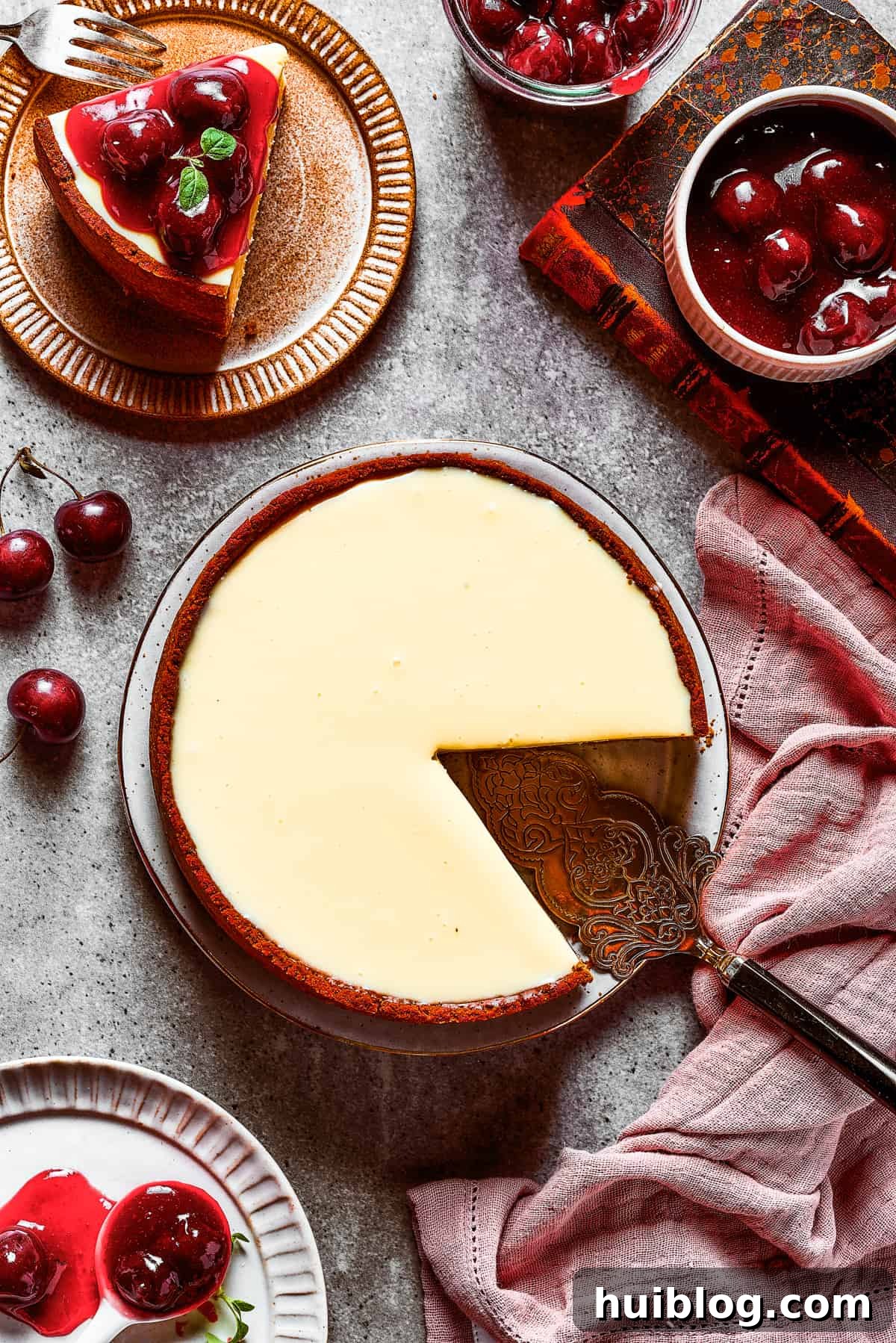 An overhead shot of a freshly baked Cherry Cheesecake with a slice elegantly removed, revealing its creamy layers and graham cracker crust.