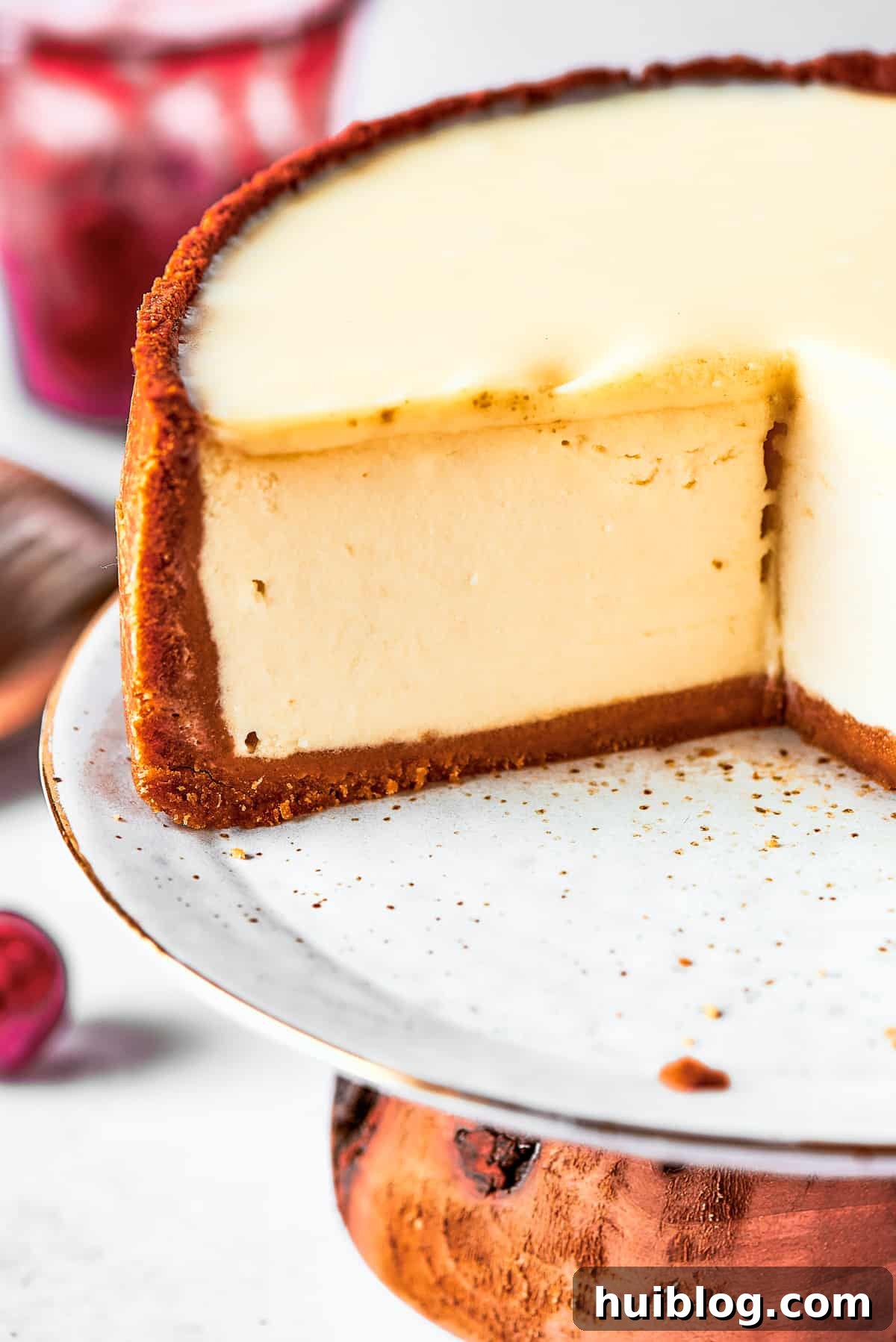 A close-up view of a perfectly sliced cherry cheesecake, showing the distinct layers of graham cracker crust, creamy cheesecake filling, and the luscious cherry topping.