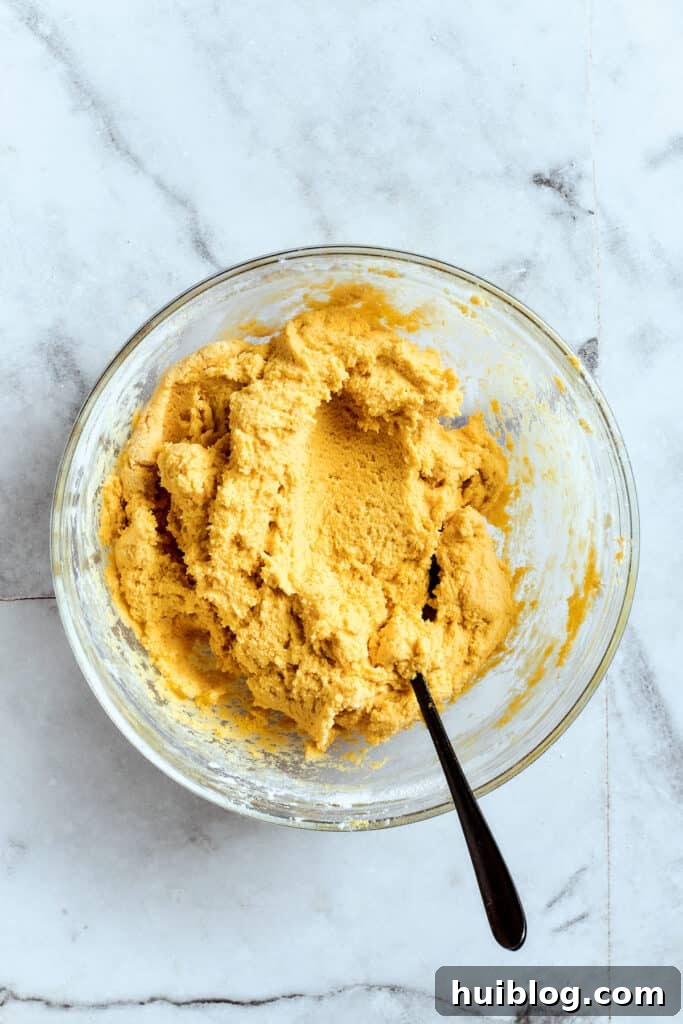 Lemon cookies are tender, soft, moist, and chewy, with tart and tangy fresh lemon flavor balanced by rich brown sugar and smooth vanilla. Overhead view of a mixing bowl filled with lemon cookie dough and a spoon.