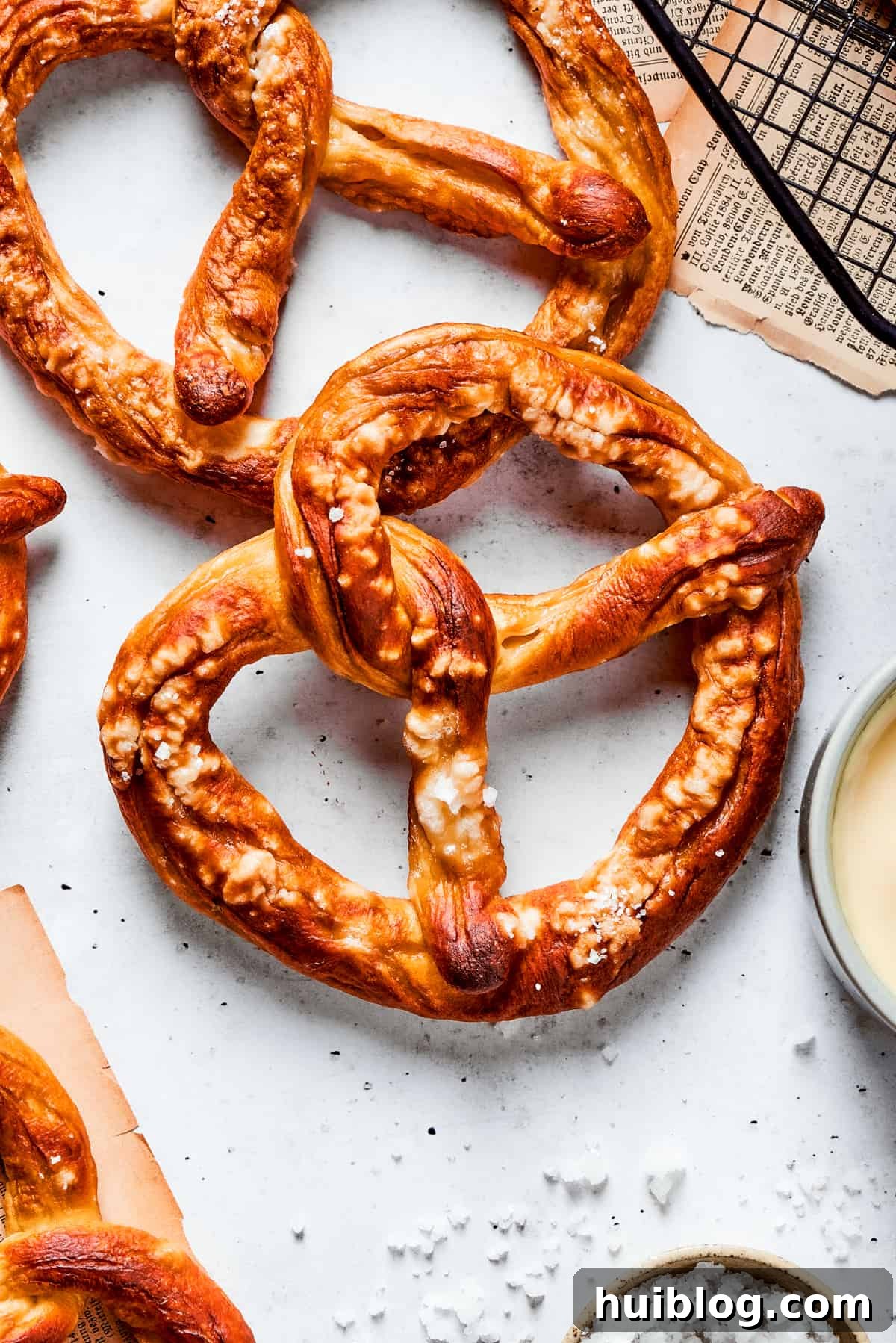 A top down shot of a baked soft pretzel, golden brown and sprinkled with coarse salt, invitingly placed for dipping.