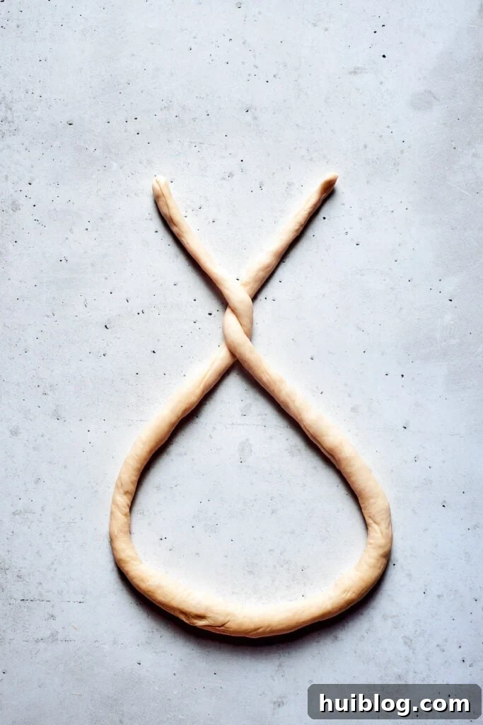 A long rope of soft pretzel dough is formed into a 'u' shape with the ends crossed over.