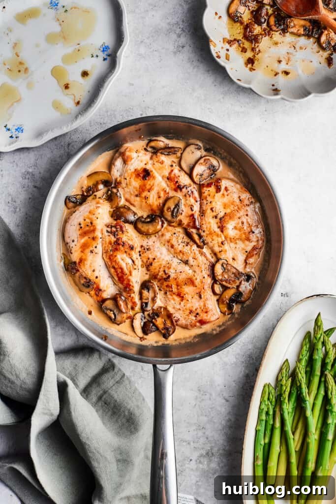 This creamy Chicken Madeira recipe is packed with savory sautéed mushrooms, sweet wine, tender chicken, and melted mozzarella cheese. A metal skillet of chicken madeira with cooked chicken, mushrooms, and a cream sauce.