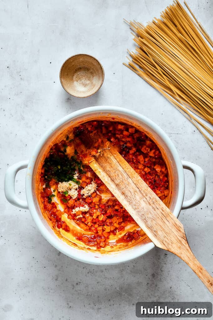 A wooden spoon stirs ingredients into a pot of spicy chicken soup, combining the rich broth with vegetables.