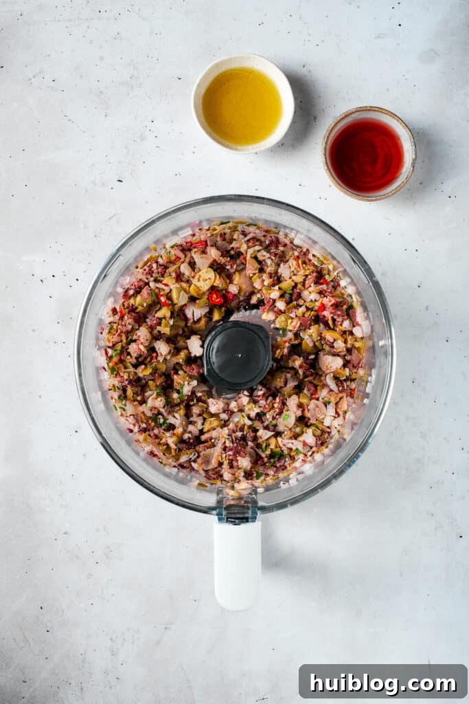 The olive salad is finely blended to a coarse texture in a food processor.