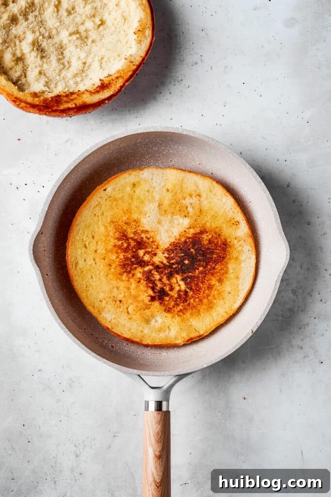 One half of the muffaletta bread is lightly toasted in a hot skillet.