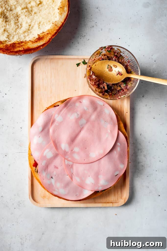 The final pieces of mortadella are carefully placed atop the other deli meats.