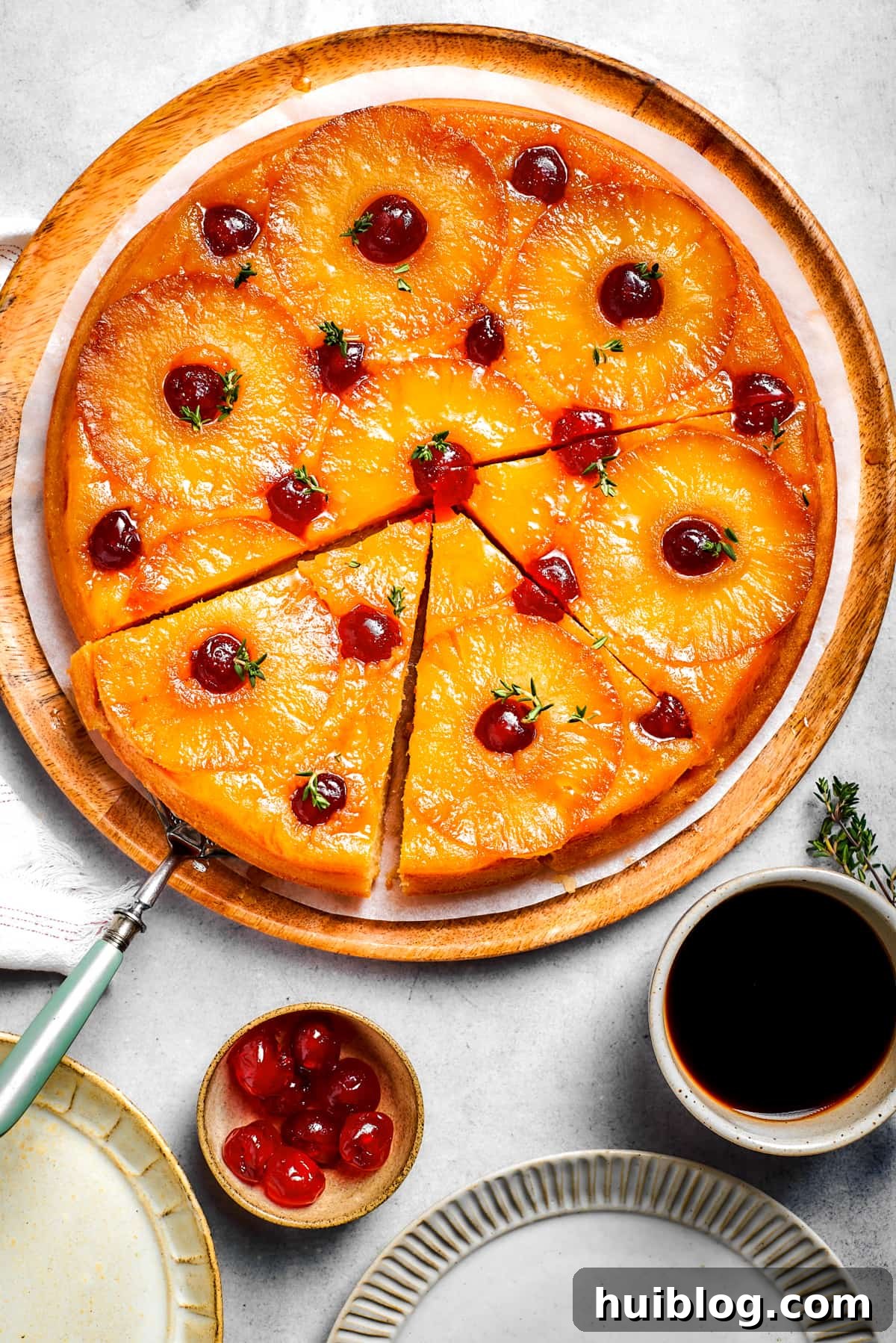A round cake topped with golden pineapple rings and vibrant red maraschino cherries, ready to be served.