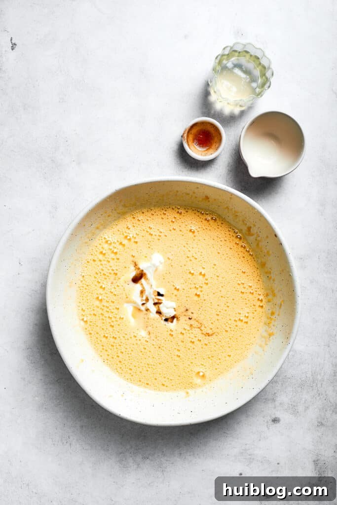 Buttermilk, sour cream, pineapple juice, and vanilla extract are poured into the wet batter, ready to be mixed.