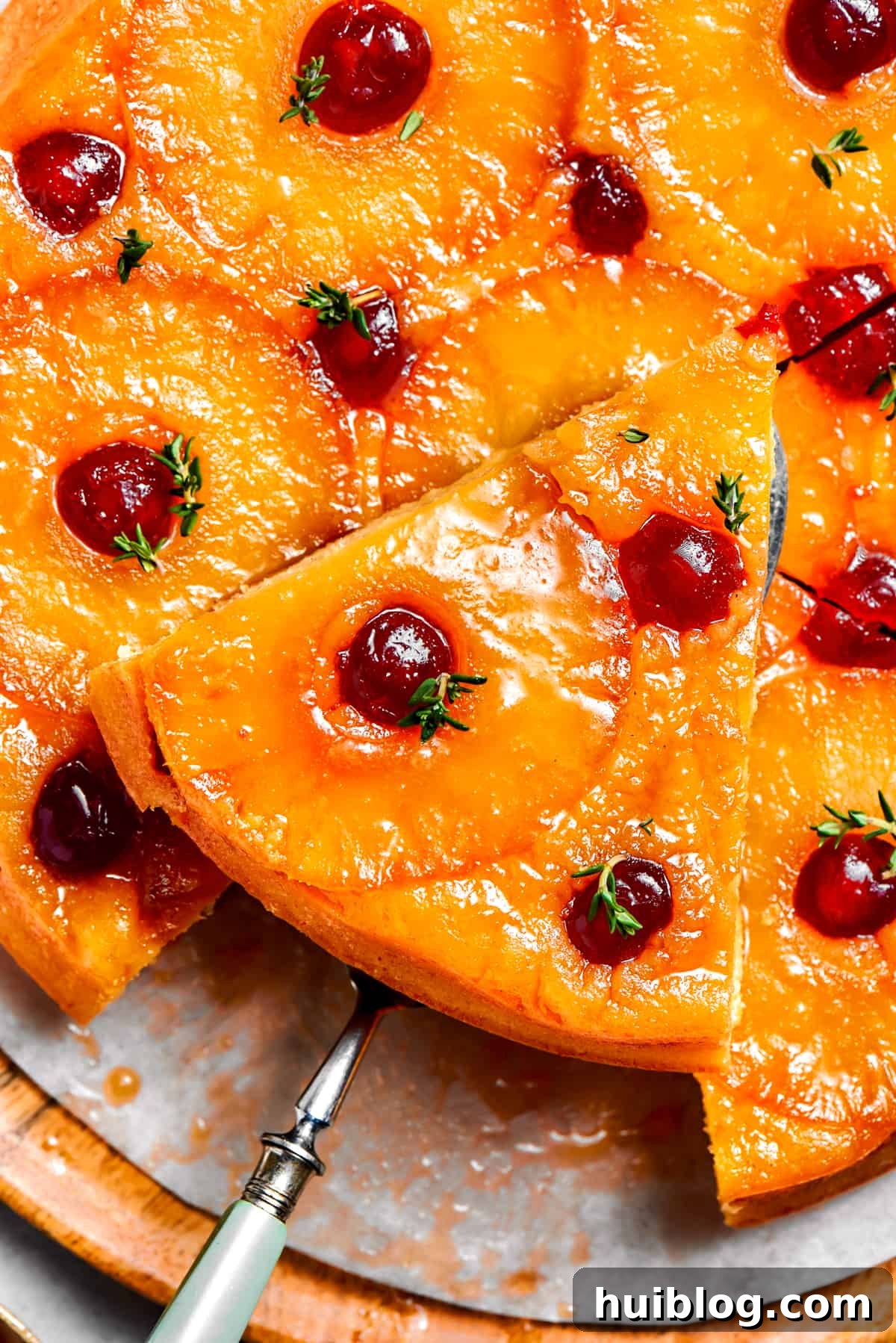 A stunning pineapple cake presented whole with a slice being removed, showcasing the tender cake and vibrant fruit topping.