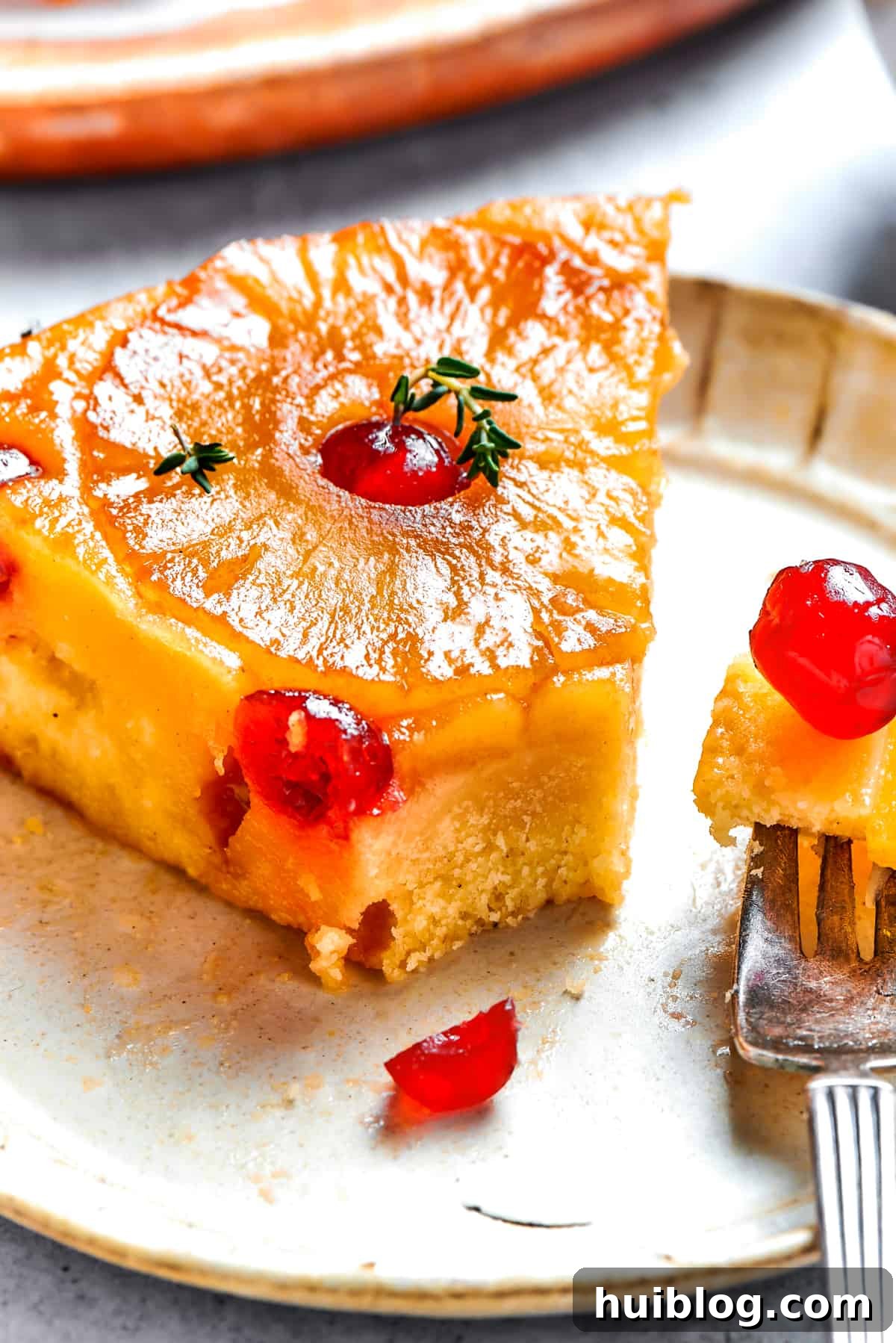 A tempting slice of pineapple cake served on a dessert plate, with a fork holding a delicious bite, highlighting the moist cake and caramelized fruit.