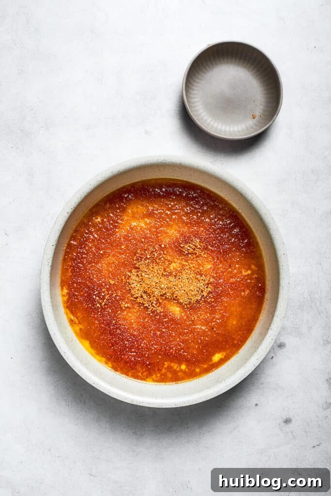 Melted butter and brown sugar are swirled together at the bottom of a round cake pan, forming the caramel base.
