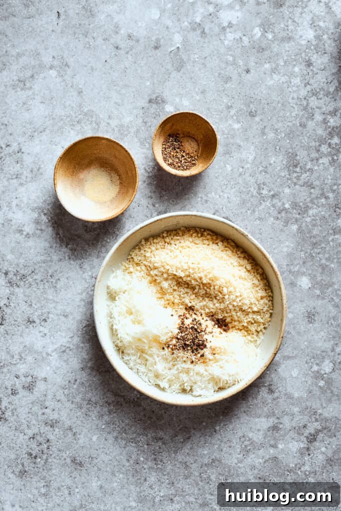 A small bowl holds a mixture of Panko breadcrumbs and Parmesan cheese, next to seasoning bowls.