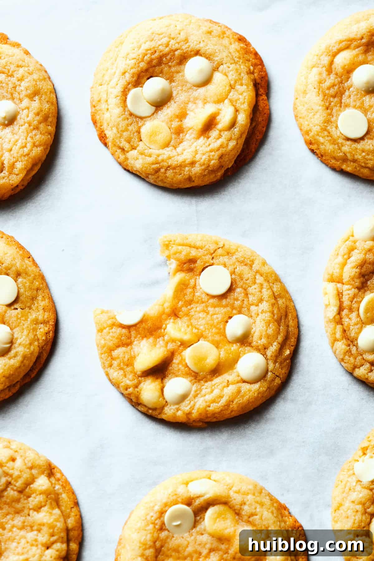 A delicious white chocolate chip cookie with a bite taken out, perfectly showcasing its soft, gooey center and the generous distribution of creamy white chocolate chips.
