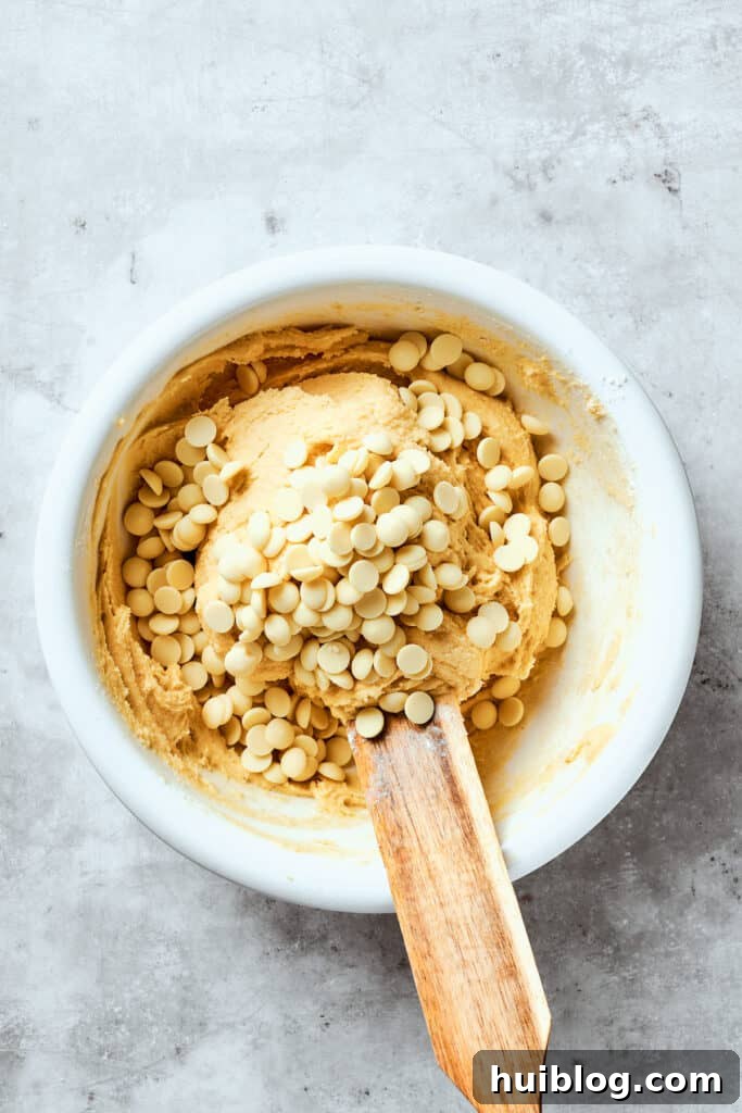 White chocolate chips are added to the dough, ready for gentle folding.