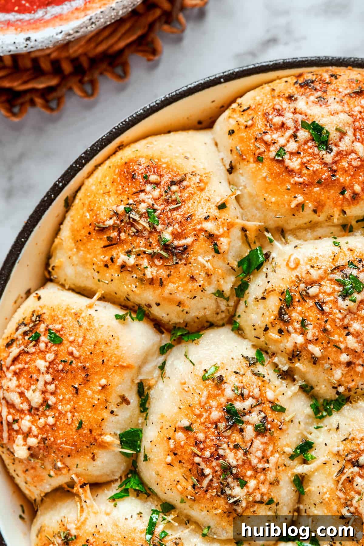 Perfectly baked pizza bites, garnished with fresh parsley. Half of the skillet of baked pizza bites topped with fresh herbs, ready to be served.